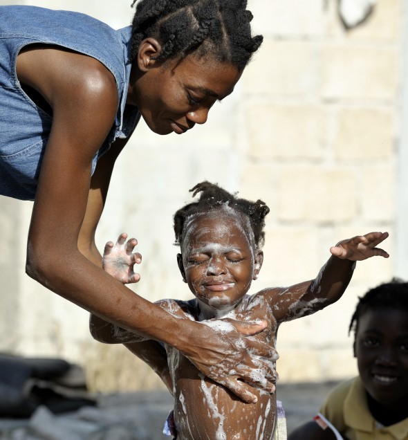 A survivor of the January 12 earthquake gives her daughter a bath amidst the rubble in the Port-au-Prince neighborhood of Belair.